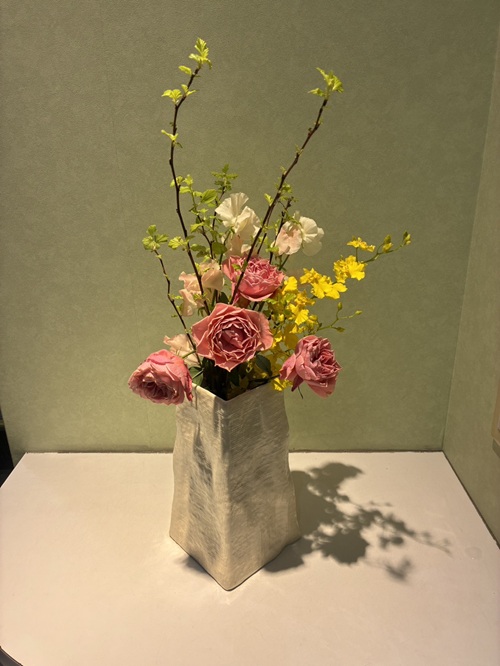 今週の院内アレンジは、可憐なスプレーバラを中心に、軽やかなスイートピー、愛らしい小手毬（コデマリ）、そして明るいオンシジュームを合わせた、やさしく華やかなアレンジです。 ふんわりとした春の空気を感じさせる色合いと動きが、院内にあたたかな雰囲気をもたらしています。 主役となるのは、繊細で愛らしい花姿のスプレーバラ。 小さな花がいくつも咲く姿は可憐で、やさしい彩りが空間に温もりを添えています。控えめながらも華やかさを感じさせる存在です。 そのやわらかさに寄り添うのがスイートピー。 ひらひらとした花びらとやさしい色合いが、アレンジ全体に軽やかさとやわらかな動きを生み出します。ほのかな香りも心を和ませてくれます。 自然な美しさを添えるのが小手毬（コデマリ）。 枝先に連なる白い小花が、リズミカルな動きと清楚な印象をプラスし、全体にやさしい広がりをもたらしています。 そして、明るさを加えるのがオンシジューム。 小さな花が軽やかに揺れるように咲き、アレンジに華やぎとリズムを与えています。見る人の気持ちを自然と明るくしてくれる存在です。 春らしいやさしさに包まれる今週のアレンジ。 ご来院の際には、ぜひ花々のやわらかな表情を楽しみながら、ほっと心安らぐひとときをお過ごしください。